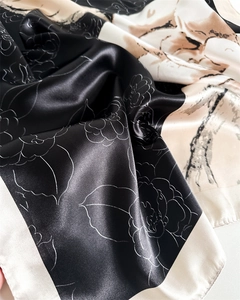 Macro detail of satin silk scarf showing elegant floral line art and smooth draped texture