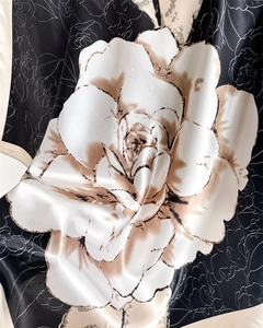 Macro shot of satin silk scarf detailing white rose print on black fabric