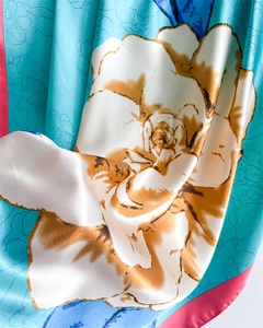 Detail of silk satin scarf showing large floral prints and vibrant blue fabric texture