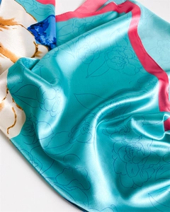 Detail of silk satin scarf featuring turquoise floral prints and magenta rolled edges