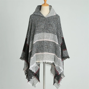Détail d'un poncho à capuche avec motif chevrons gris et bordures à franges chaudes
