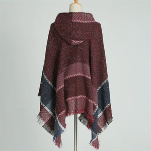 Détail d'un poncho à capuche à carreaux avec tricot à chevrons rouge vin et bleu et franges