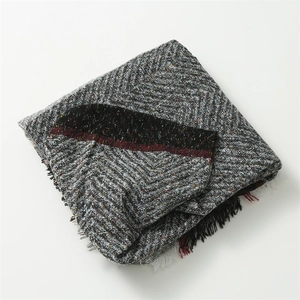 Macro shot of grey herringbone weave pattern with colorful speckles and fringe detail