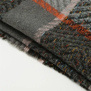 Close-up of thick plaid shawl with orange and grey weave and soft fringe detail