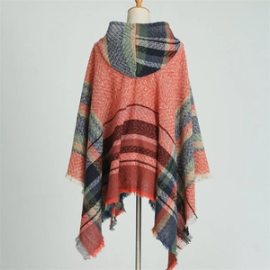 Detail of red and orange plaid hooded poncho with knit texture and fringe trim