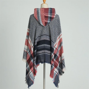 Detail view of hooded knit poncho with plaid pattern, fringe hem, and thick winter texture
