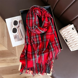 Detailed view of red plaid cashmere scarf with soft tassels in a stylish winter setting