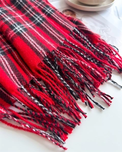 Detailed view of red and black plaid cashmere scarf featuring elegant fringe tassels