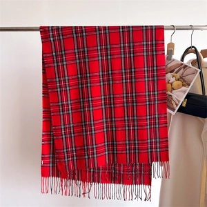 Detail of red and black plaid scarf with fringe edge on display with stylish accessories