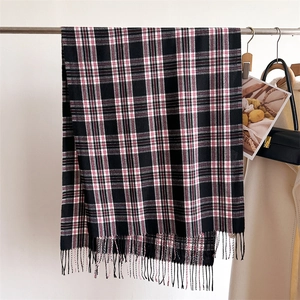 Close-up of black and red plaid scarf with tassel fringe on a metal display rack