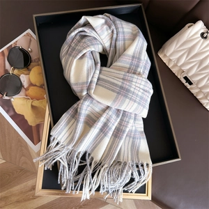 Detailed view of soft plaid cashmere-like scarf with tassels on an elegant tray