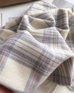 Close-up of soft plaid scarf with fringe in beige, grey and pink cashmere-like fabric