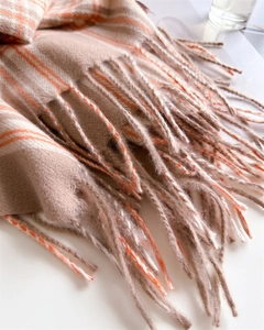 Close-up of beige and orange plaid winter scarf with soft fringed tassel details