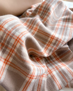 Detailed macro shot of warm orange plaid scarf with soft cashmere-like texture
