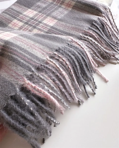 Detailed close-up of thick plaid cashmere scarf with grey, pink and white fringe