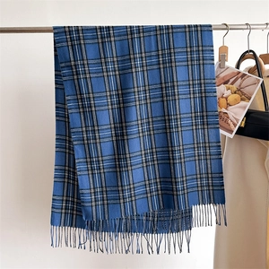 Close-up of blue plaid cashmere-like scarf with soft fringe hanging on a metal rod