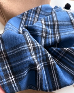 Macro detail of soft blue and black plaid scarf texture with premium cashmere-like fringe