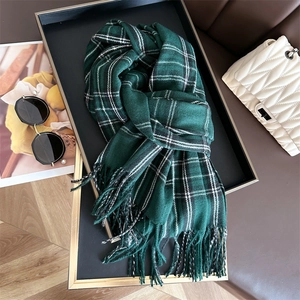 Detailed close-up of a green plaid scarf with soft tassels and premium woven texture