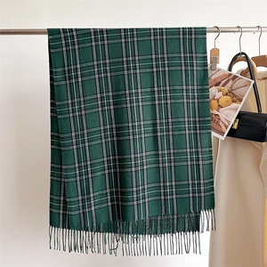 Close-up of green plaid scarf with soft fringe detail and woven wool texture