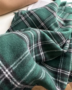 Close-up of forest green plaid scarf with soft tassels and thick woven wool texture