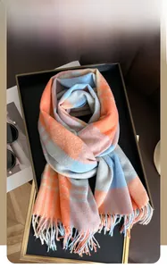 Close-up of thick rainbow plaid scarf with orange and blue fringe on a black tray