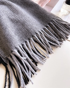 Nahaufnahme von grauem Strickschal mit eleganten langen Fransen und weicher Textur