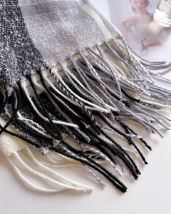 Close-up of black and white checkered scarf showing fringe tassels and thick knit texture