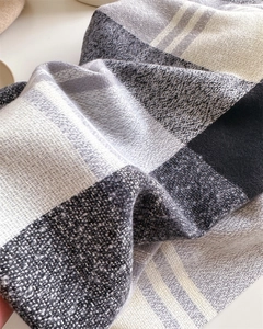 Detailed texture of cashmere-like rainbow plaid scarf with soft fringe and thick weave