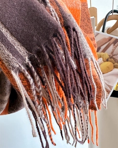 Detail of color-block scarf featuring orange, brown, grey stripes and thick twisted tassels