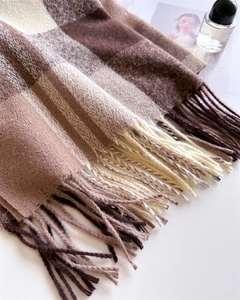 Detailed texture of a thick plaid scarf with long fringes in coffee and beige tones
