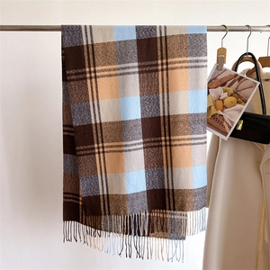Detail of soft cashmere-feel rainbow plaid scarf with long fringes hung on a metal rack