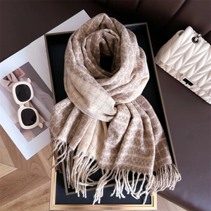 Écharpe à carreaux beige et marron à franges sur un plateau déco avec accessoires
