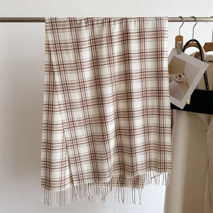 Détail du foulard en cachemire à carreaux beige avec franges et texture tissée