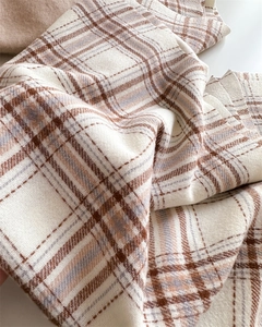 Gros plan sur la texture épaisse du tricot à carreaux avec franges beige et marron café