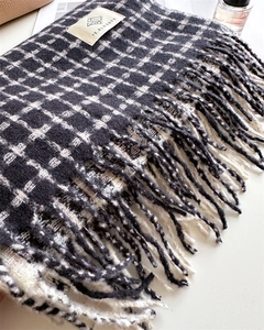 Détail de l'écharpe à carreaux noir et blanc avec de longues franges et étiquette tissée