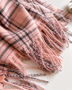 Gros plan sur la texture de l'écharpe à carreaux rose avec franges et tissage délicat