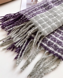 Gros plan d'une écharpe à carreaux violet et gris en cachemire avec de longues franges