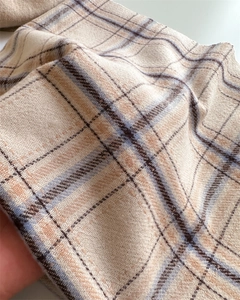 Gros plan d'une écharpe en cachemire à carreaux beige avec tissage sergé et franges
