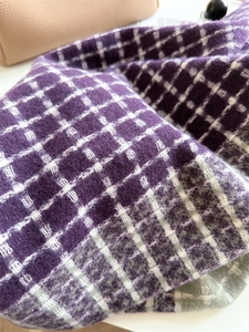 Gros plan d'une écharpe en cachemire à carreaux violets et beiges, maille douce