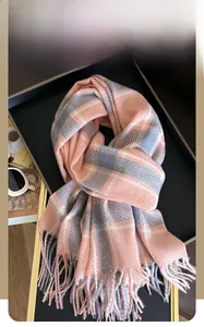 Detail eines rosa-grau karierten Winterschals mit Fransen, gefaltet auf einem Tablett