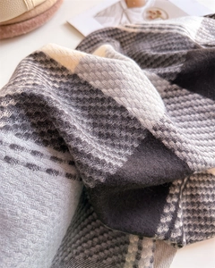 Dettaglio della trama di una sciarpa a quadri spessa in maglia simil-cashmere grigio e beige