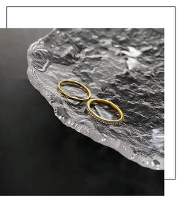 Close-up of gold-plated titanium rings with zircons on a glass tray for women