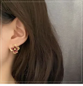 Close-up of deep red petal flower earrings with golden core on model side profile
