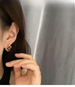 Model wearing pink floral stud earrings with gold accents and translucent petals