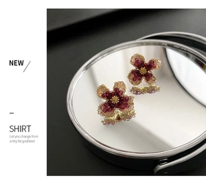 Detailed macro of handcrafted floral studs featuring ruby red beads and a gold center