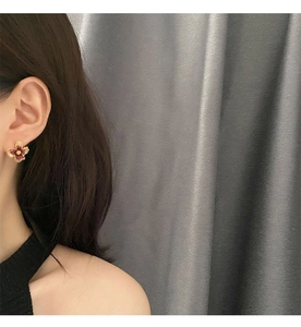 Close-up of pink flower earrings with gold edges worn by a model for size reference