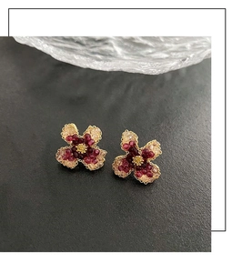 Detailed close-up of pink beaded flower stud earrings with gold-plated petals on gray background