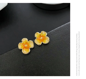 Detailed macro view of yellow floral stud earrings with resin petals and golden stamen
