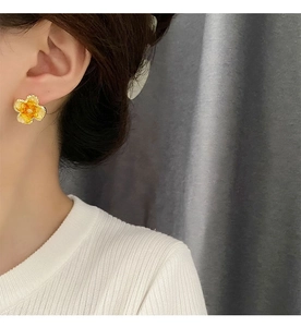 Close-up of a sweet orange flower earring made of resin with s925 silver stud on ear