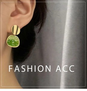 Dettaglio di orecchini s925 oro con texture ghiaia verde sfumata su una modella reale